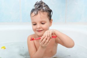 plan-petit-enfant-se-brossant-dents-pendant-bain-charmante-dame-mouillee-tient-brosse-dents-rouge