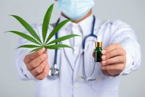 medecin-tenant-feuille-cannabis-bouteille-huile-cannabis-mur-blanc