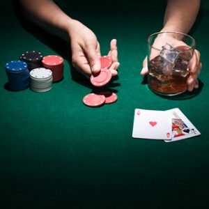 personne-tenant-verre-whisky-jouant-carte-poker